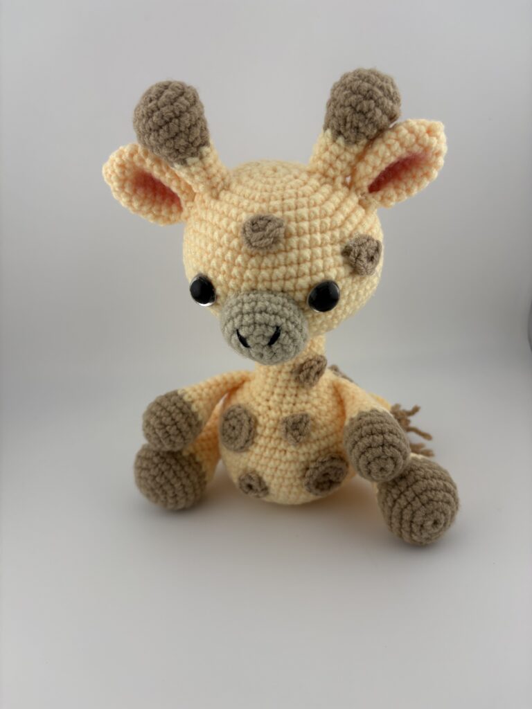 Amigurumi Giraffe crocheted in light yellow yarn with light brown spots.